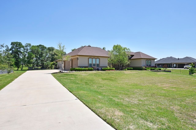 view of front of home with driveway, a front lawn, an attached garage, and stucco siding