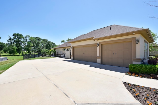 view of home's exterior featuring a shingled roof, driveway, and stucco siding