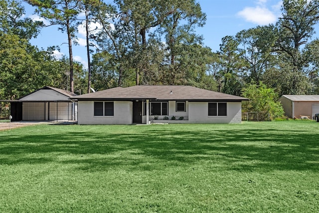 rear view of property featuring a garage, a yard, fence, and an outbuilding