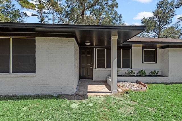 entrance to property with a lawn and brick siding