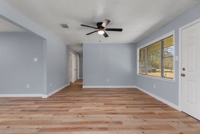 interior space with visible vents, baseboards, a ceiling fan, light wood-style flooring, and a textured ceiling