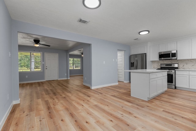 kitchen featuring tasteful backsplash, appliances with stainless steel finishes, a center island, light countertops, and white cabinetry