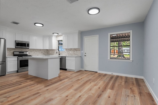 kitchen with visible vents, decorative backsplash, a center island, stainless steel appliances, and light countertops