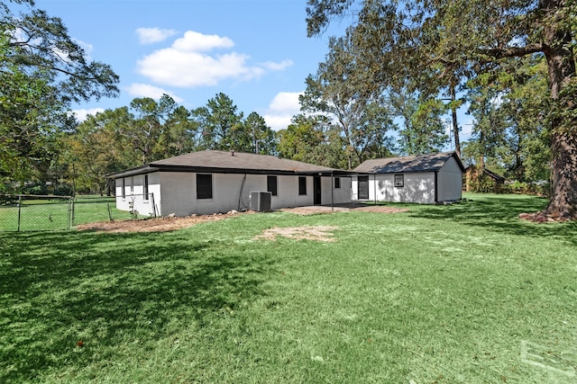 rear view of property featuring central AC unit, fence, and a yard