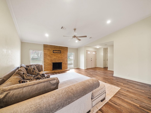 living room with baseboards, visible vents, wood finished floors, and ornamental molding