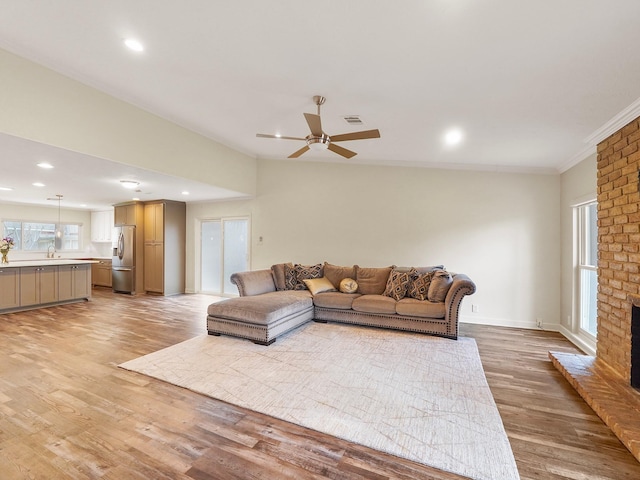 living room with light wood finished floors, a fireplace, a ceiling fan, and recessed lighting