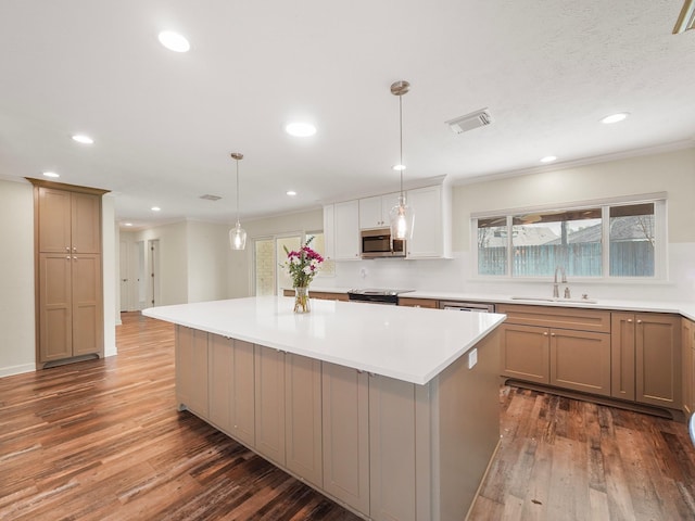 kitchen with visible vents, a kitchen island, wood finished floors, stainless steel appliances, and a sink