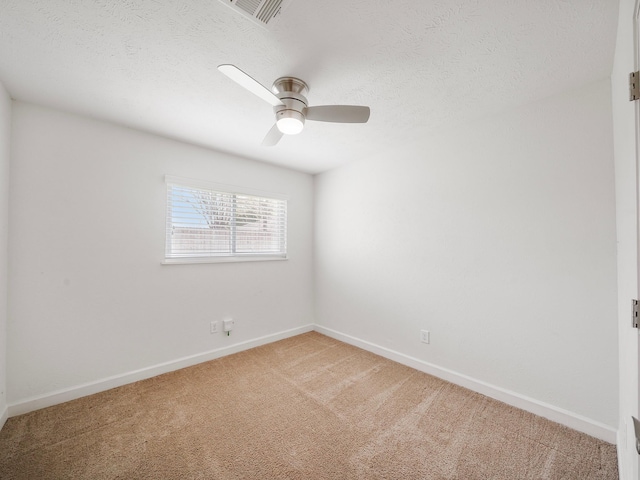 spare room with a textured ceiling, baseboards, visible vents, and light colored carpet