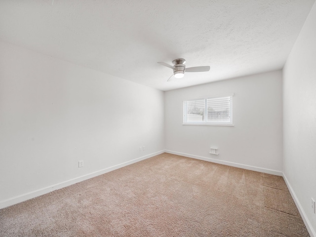 empty room with a ceiling fan, light colored carpet, a textured ceiling, and baseboards