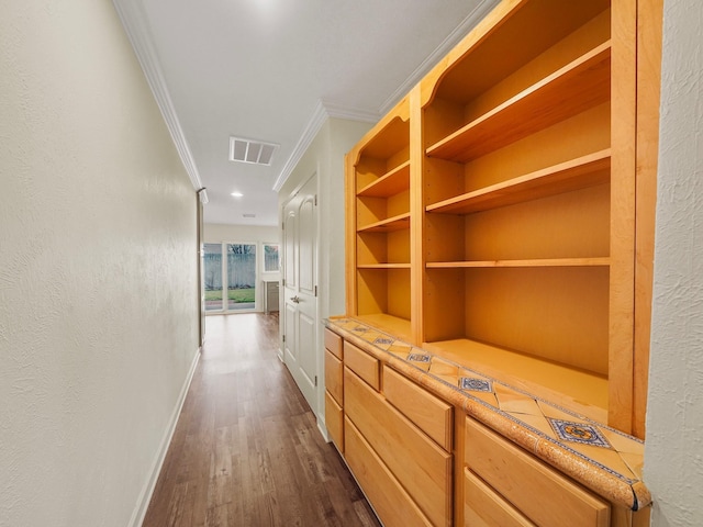 corridor featuring baseboards, dark wood-style flooring, visible vents, and crown molding