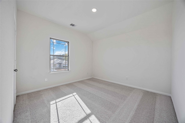 carpeted spare room featuring lofted ceiling, visible vents, and baseboards