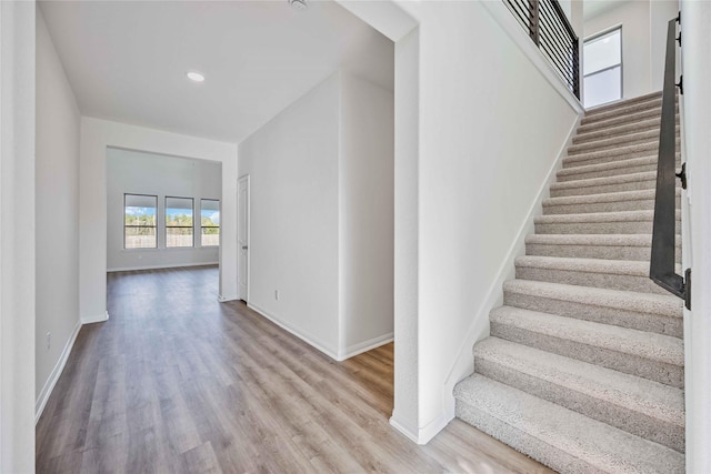 stairway with recessed lighting, wood finished floors, and baseboards