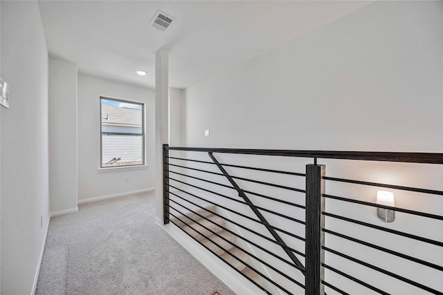 hallway with carpet floors, visible vents, and baseboards