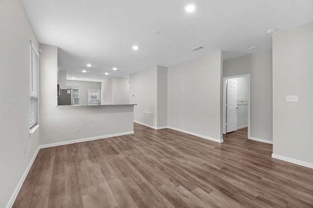 unfurnished living room with recessed lighting, visible vents, baseboards, and wood finished floors