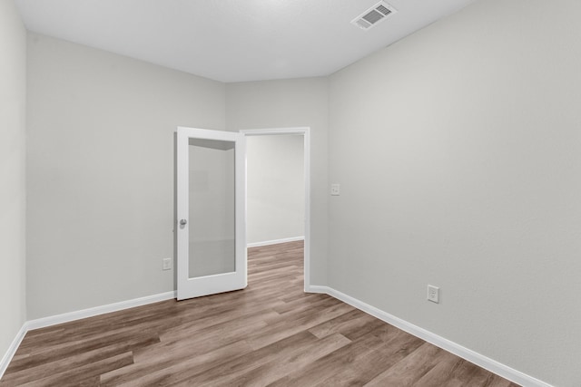 empty room featuring wood finished floors, visible vents, and baseboards