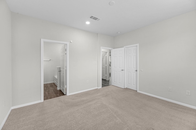 unfurnished bedroom with recessed lighting, carpet floors, visible vents, baseboards, and ensuite bath