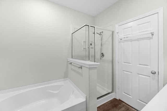 full bath with a stall shower, a bath, and wood finished floors