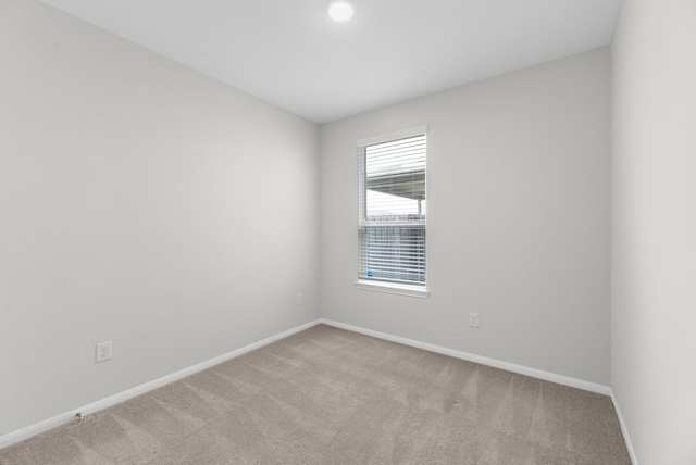 unfurnished room featuring baseboards and light colored carpet