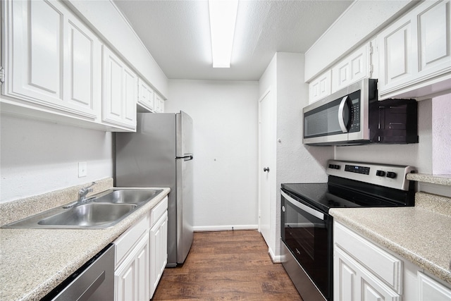 kitchen with dark wood finished floors, stainless steel appliances, light countertops, white cabinets, and a sink