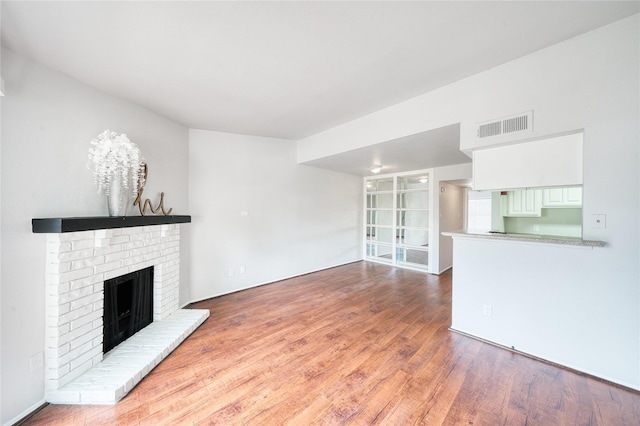 unfurnished living room featuring a fireplace, visible vents, and wood finished floors