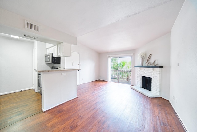 kitchen featuring visible vents, stainless steel microwave, a fireplace, and wood finished floors