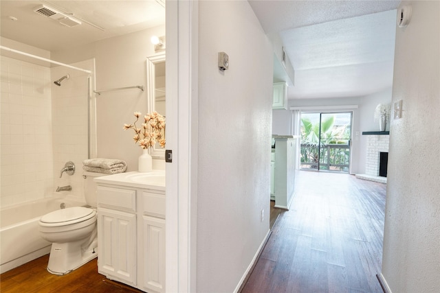 full bathroom with visible vents, toilet, wood finished floors, vanity, and a fireplace