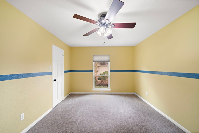 carpeted empty room with a ceiling fan and baseboards