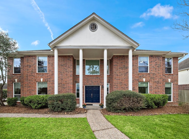 neoclassical home with a front yard and brick siding