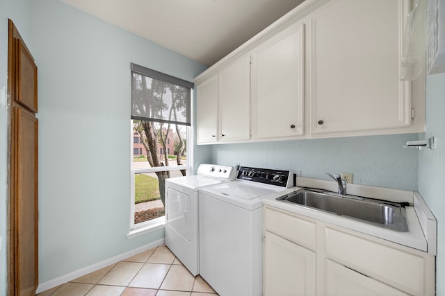 clothes washing area featuring cabinet space, light tile patterned floors, baseboards, washing machine and dryer, and a sink