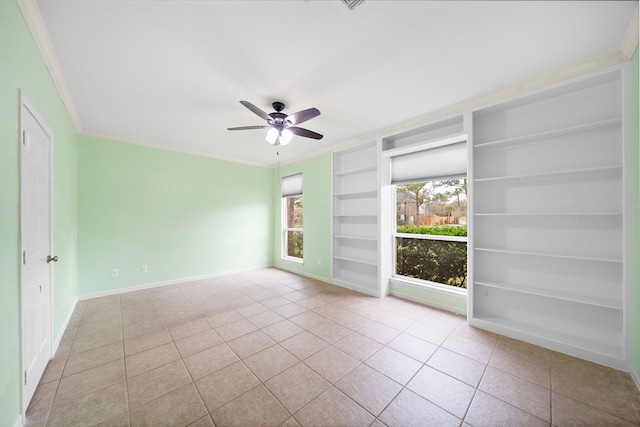 tiled spare room featuring built in shelves, ornamental molding, a ceiling fan, and baseboards