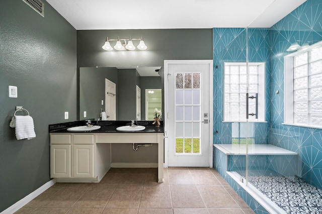 bathroom with a stall shower, visible vents, a sink, and tile patterned floors