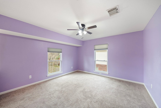 empty room featuring a ceiling fan, carpet, visible vents, and baseboards