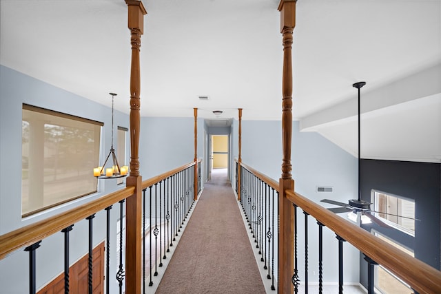 hall featuring carpet flooring, vaulted ceiling, visible vents, and an inviting chandelier