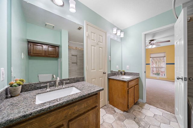 bathroom with visible vents, two vanities, a sink, and tiled shower