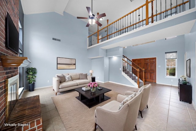 living area featuring stairway, a brick fireplace, tile patterned flooring, and baseboards