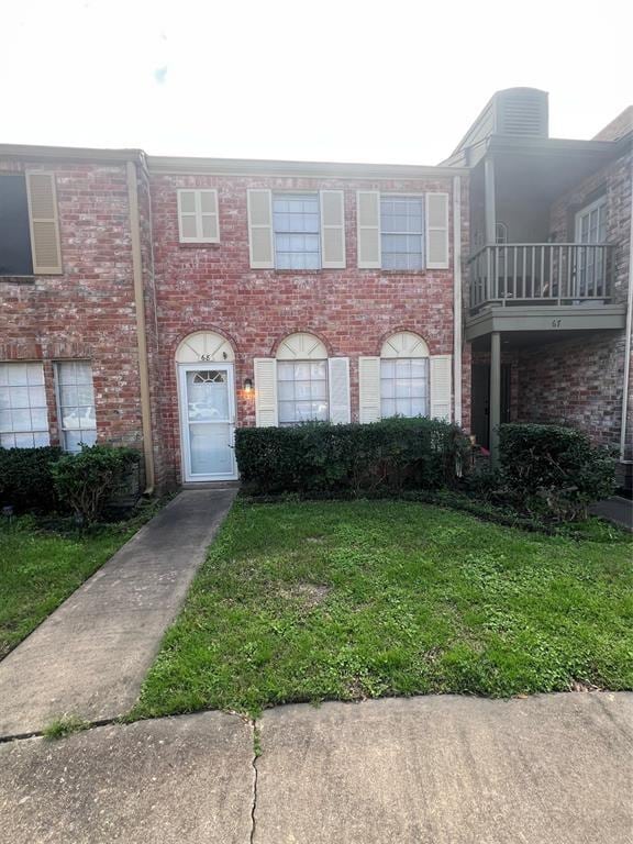 townhome / multi-family property featuring a front yard and brick siding