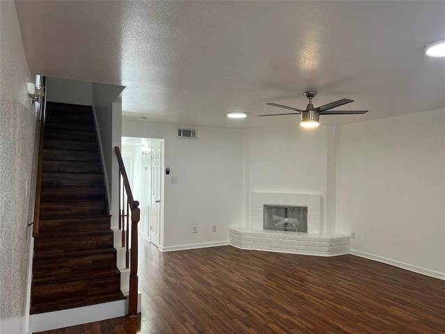 unfurnished living room featuring baseboards, a fireplace, stairway, and wood finished floors