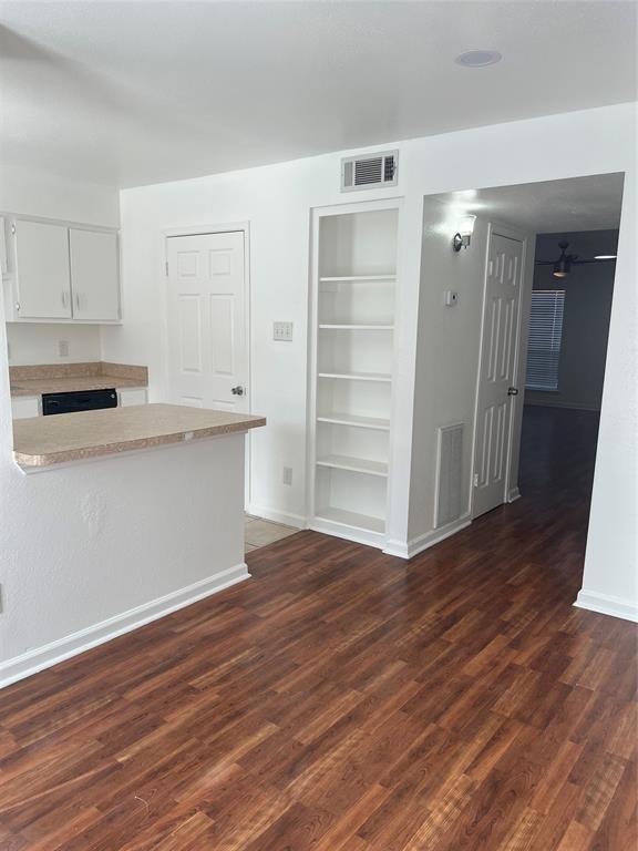 interior space with visible vents, built in features, dark wood-style flooring, light countertops, and white cabinetry