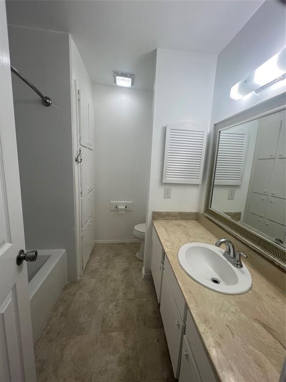 bathroom featuring toilet, a bathing tub, and vanity