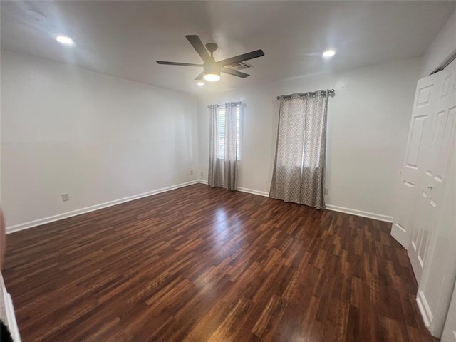 spare room featuring ceiling fan, baseboards, and dark wood finished floors