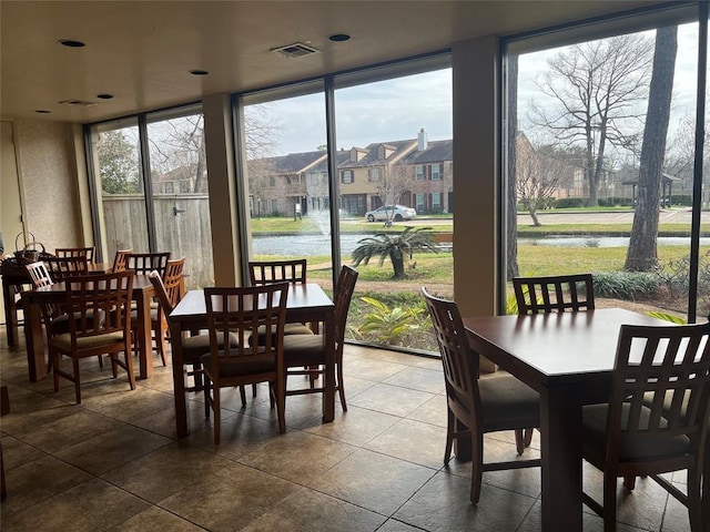 tiled dining room featuring expansive windows, visible vents, and a residential view