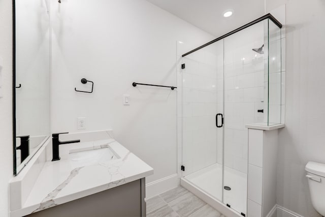 full bath with a stall shower, baseboards, vanity, and toilet