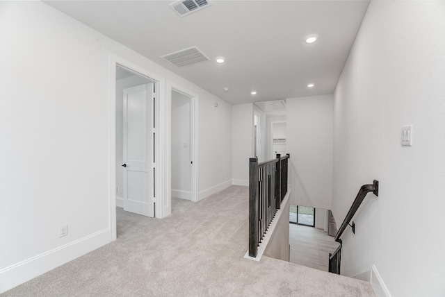 corridor featuring visible vents, carpet, an upstairs landing, and attic access