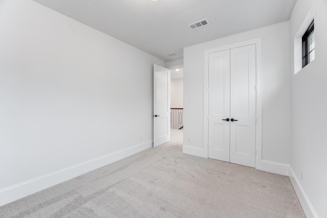 unfurnished bedroom featuring carpet, a closet, visible vents, and baseboards