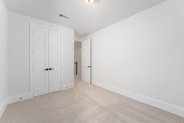 unfurnished bedroom featuring a closet, carpet flooring, visible vents, and baseboards