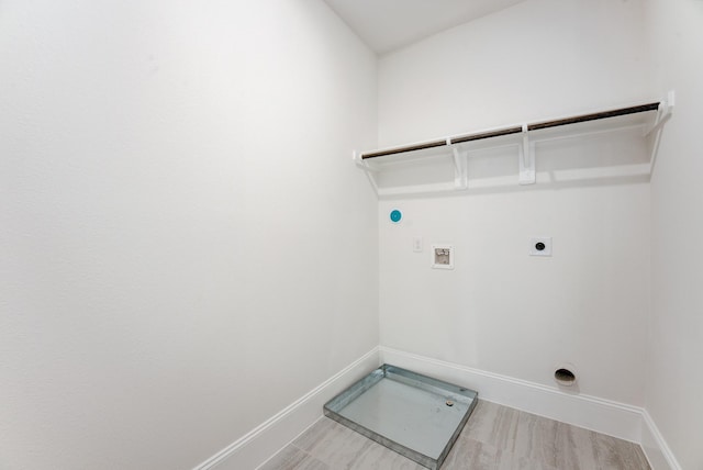 clothes washing area with washer hookup, electric dryer hookup, wood finished floors, laundry area, and baseboards