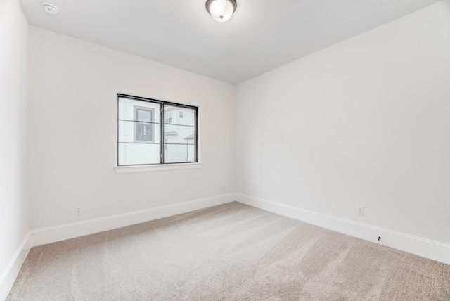 carpeted empty room featuring baseboards