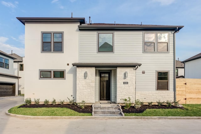 view of front of house with a garage, stone siding, and fence