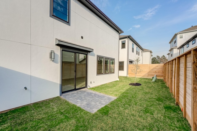 rear view of house featuring a patio area, a fenced backyard, a lawn, and stucco siding