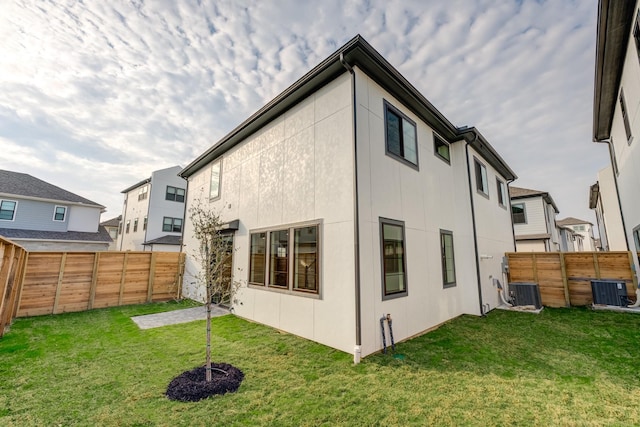 back of property with a yard, central AC, and a fenced backyard